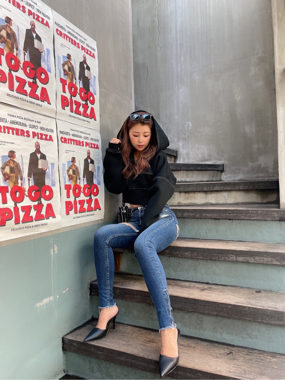 ブラック系のパンプス、ブルー系のデニムパンツ、ブラック系のパーカーを着用したレディースの秋コーディネートの2枚目の写真