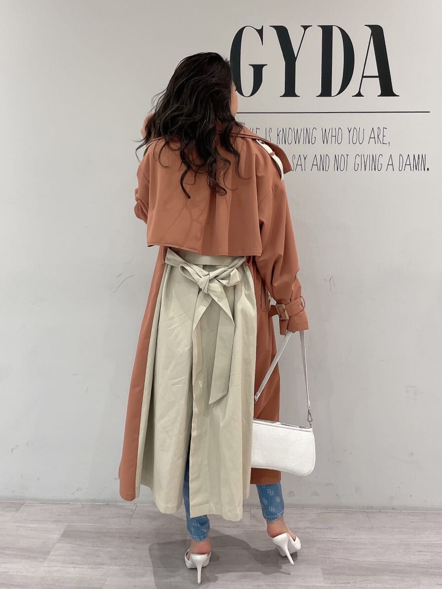 ホワイト系のキャミソール、ホワイト系のパンプス、オレンジ系のトレンチコートを着用したレディースの春コーディネートの3枚目の写真