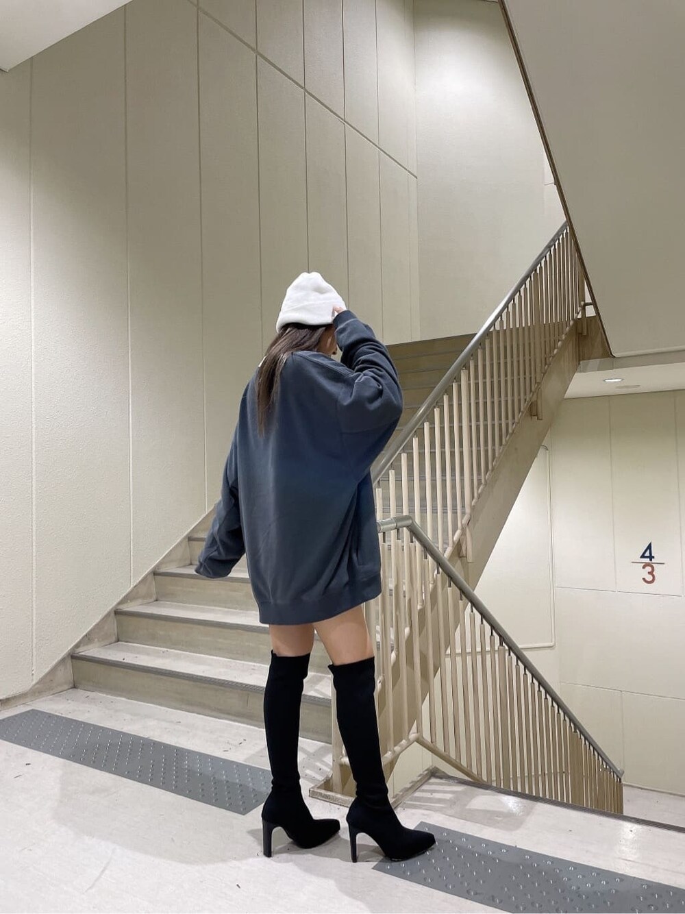 ブラック系のブーツ、グレー系のスウェット、ホワイト系のニットキャップ/ビーニーを着用したレディースの秋コーディネートの2枚目の写真