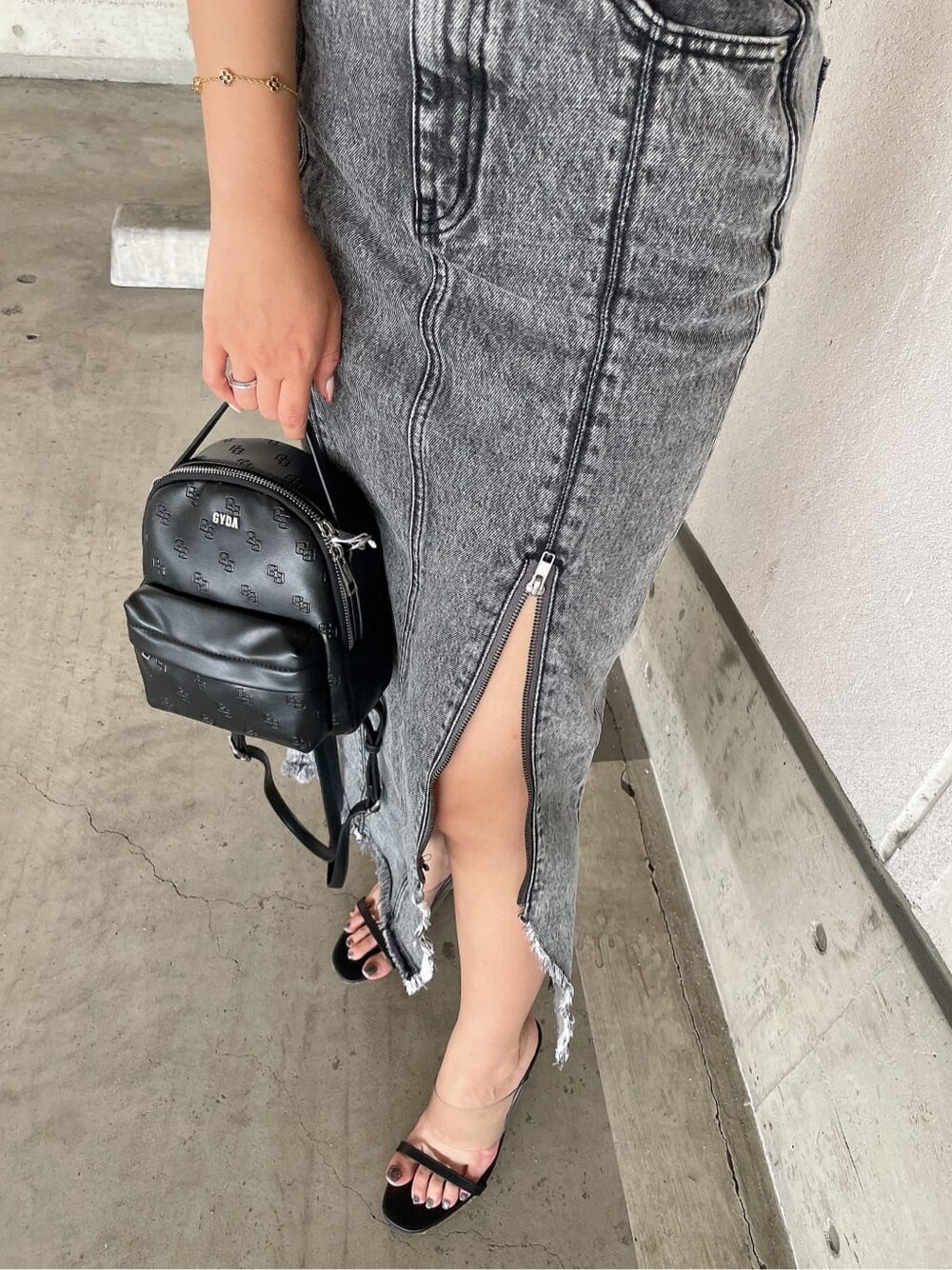 ブラック系のサンダル、ブラック系のバックパック/リュック、ブラック系のデニムスカートを着用したレディースの夏コーディネートの7枚目の写真