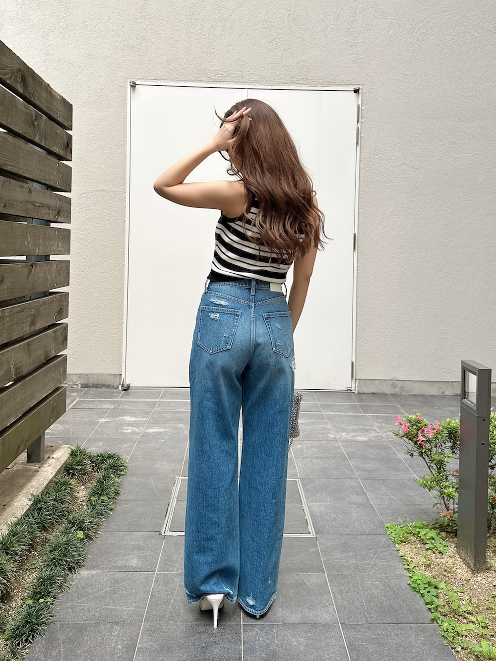 ブルー系のデニムパンツ、ホワイト系のパンプス、ホワイト系のニット/セーターを着用したレディースの夏コーディネートの3枚目の写真