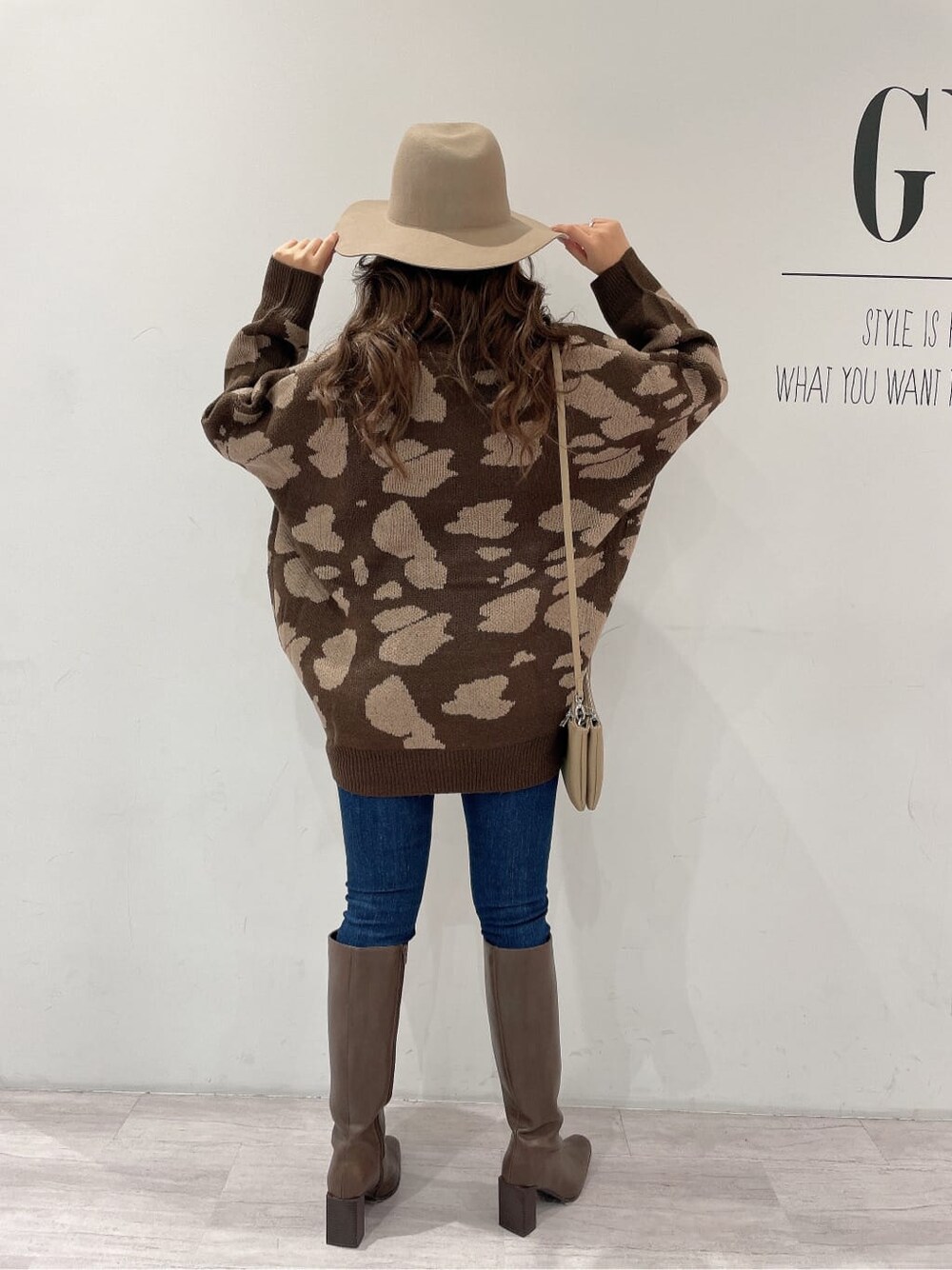 ブラウン系のブーツ、ブルー系のデニムパンツ、ベージュ系のショルダーバッグを着用したレディースの秋コーディネートの2枚目の写真