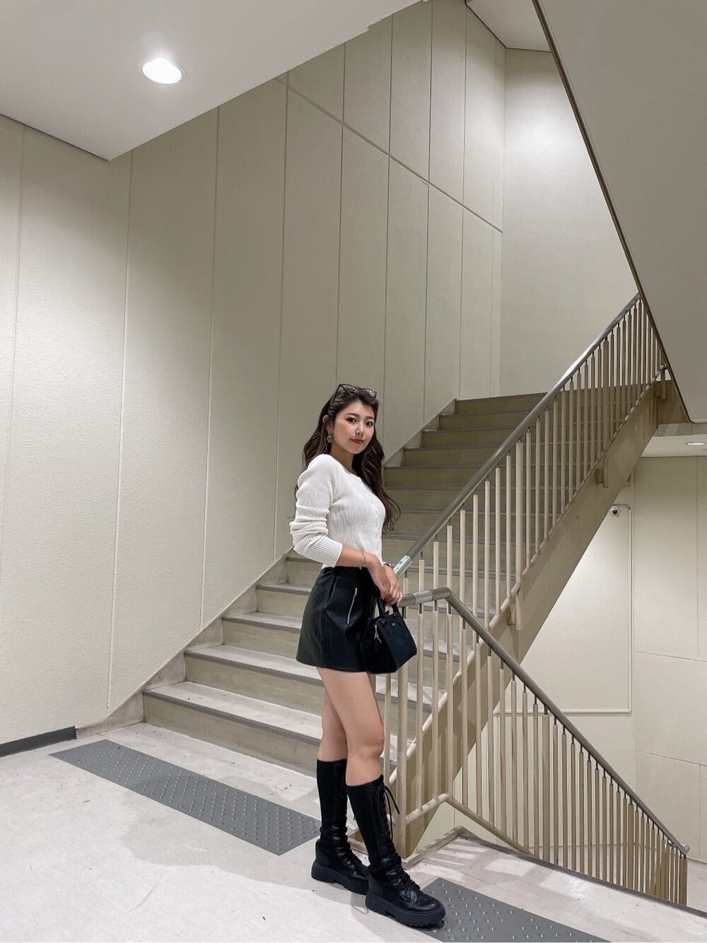 ブラック系のハンドバッグ、ブラック系のスカート、ホワイト系のカーディガン/ボレロを着用したレディースの秋コーディネートの3枚目の写真