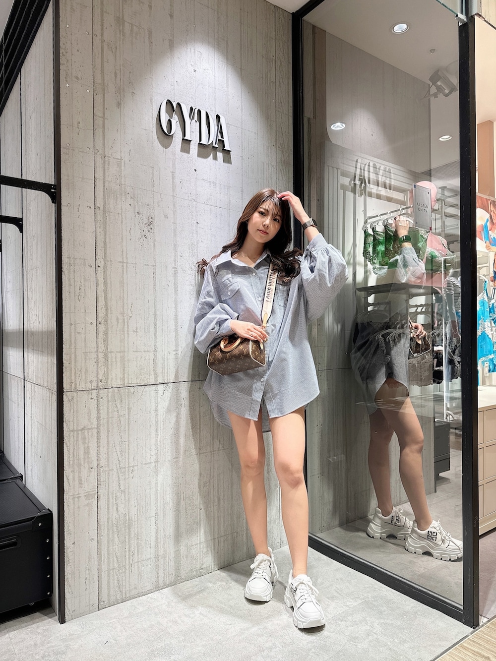 ブルー系のシャツ/ブラウス、ブラック系のスニーカーを着用したレディースの春コーディネートの2枚目の写真