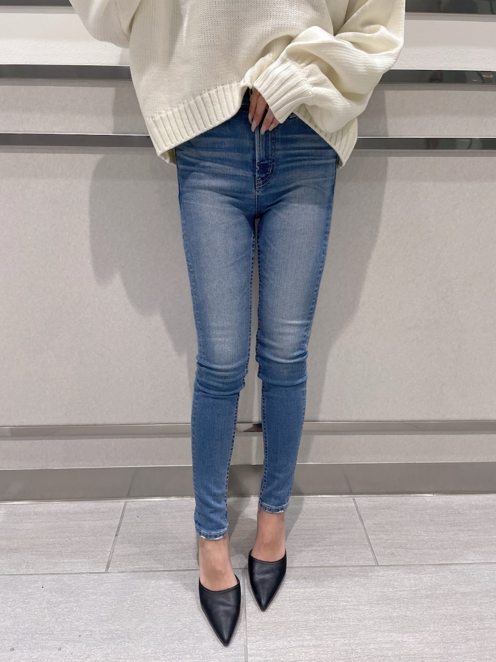 ホワイト系のニット/セーター、ブルー系のデニムパンツ、ブラック系のパンプスを着用したレディースの冬コーディネートの5枚目の写真
