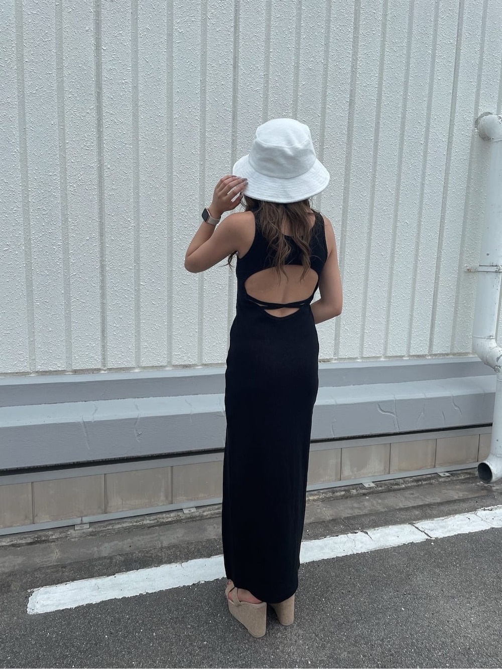 ホワイト系のサンダル、ホワイト系のハンドバッグ、ブラック系のワンピースを着用したレディースの夏コーディネートの4枚目の写真