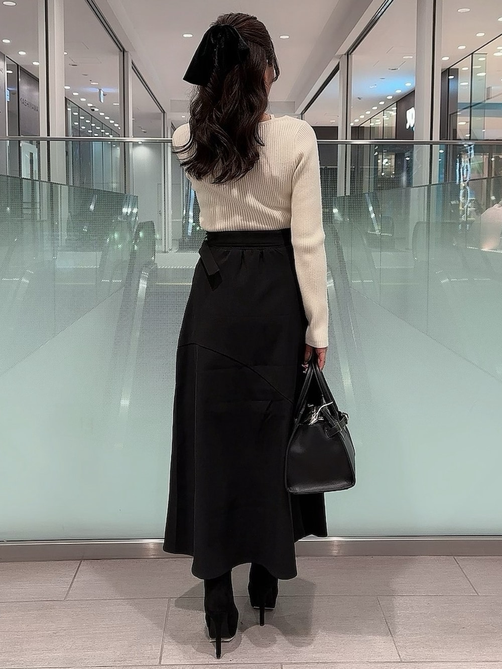 ホワイト系のニット/セーター、ブラック系のスカート、ブラック系のブーツを着用したレディースの冬コーディネートの3枚目の写真