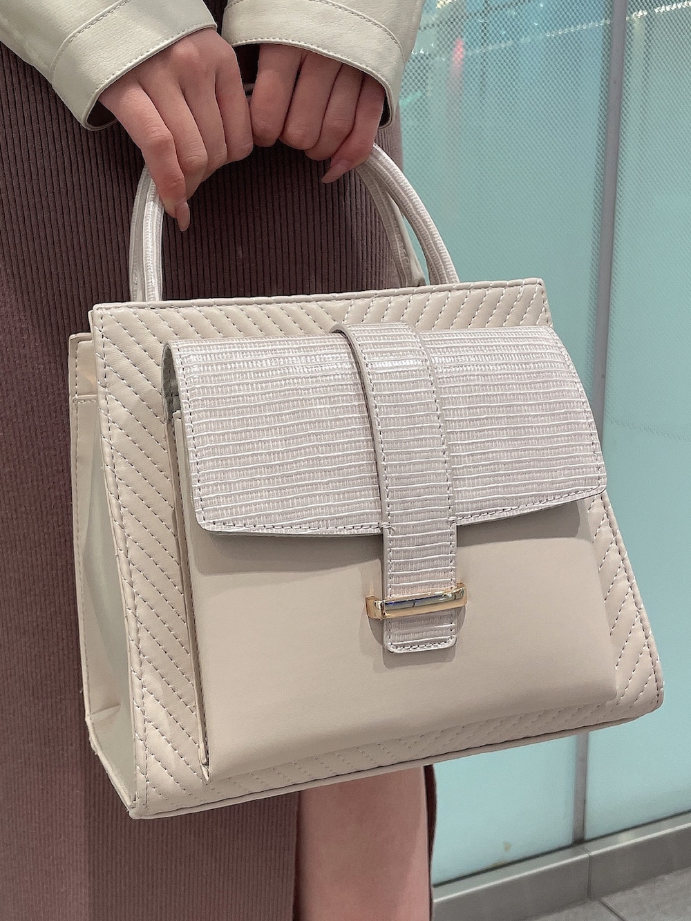 ブラック系のワンピース、ホワイト系のライダースジャケット、ホワイト系のパンプスを着用したレディースの冬コーディネートの7枚目の写真