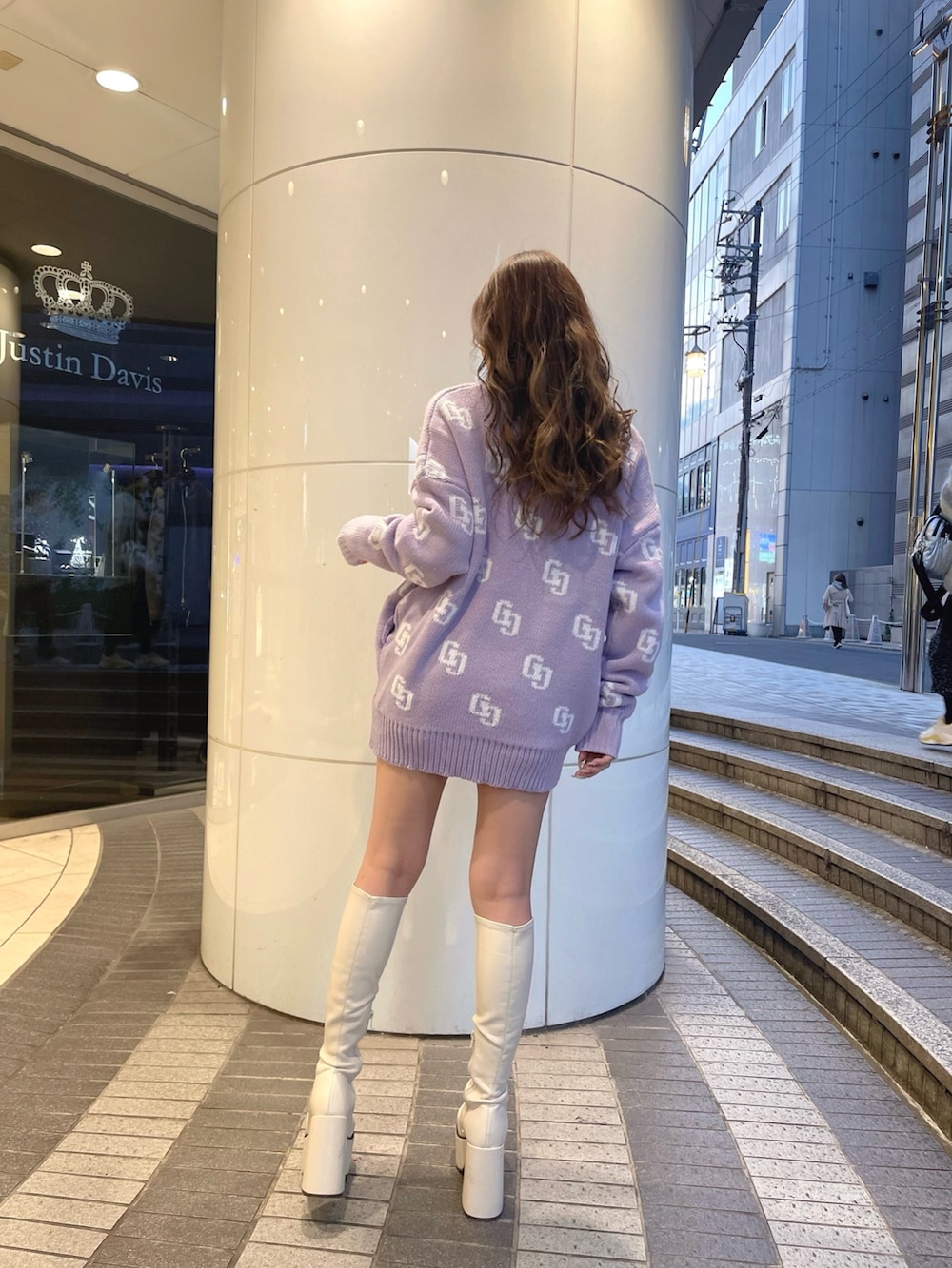 パープル系のニット/セーター、ブラック系のデニムパンツ、ホワイト系のブーツを着用したレディースの冬コーディネートの2枚目の写真