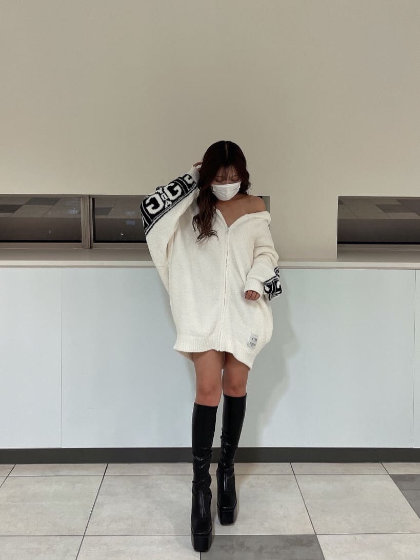 ブラック系のブーツ、ブラック系のスカート、ホワイト系のカーディガン/ボレロを着用したレディースの秋コーディネートの2枚目の写真