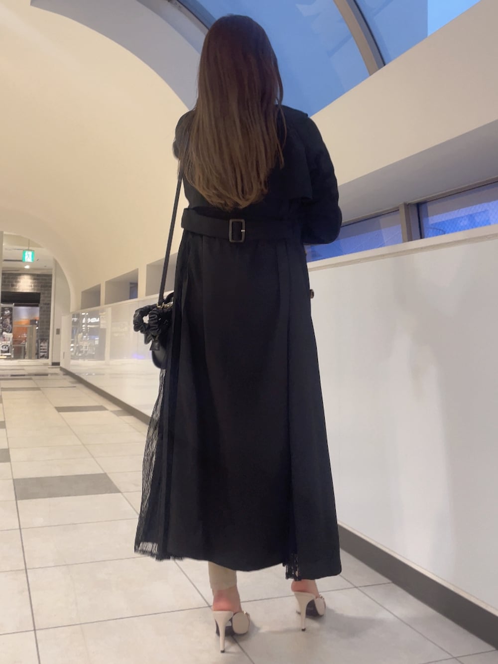 ブラック系のトレンチコート、ブラック系のニット/セーター、ブラック系のハンドバッグを着用したレディースの春コーディネートの3枚目の写真