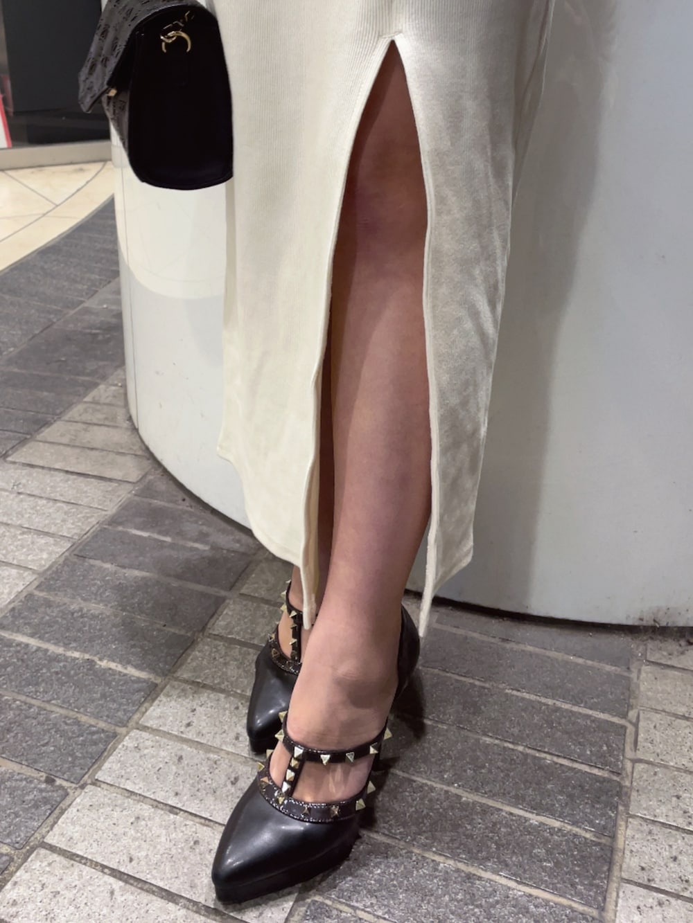 ホワイト系のワンピース、ブラック系のハンドバッグ、ブラック系のパンプスを着用したレディースの冬コーディネートの6枚目の写真