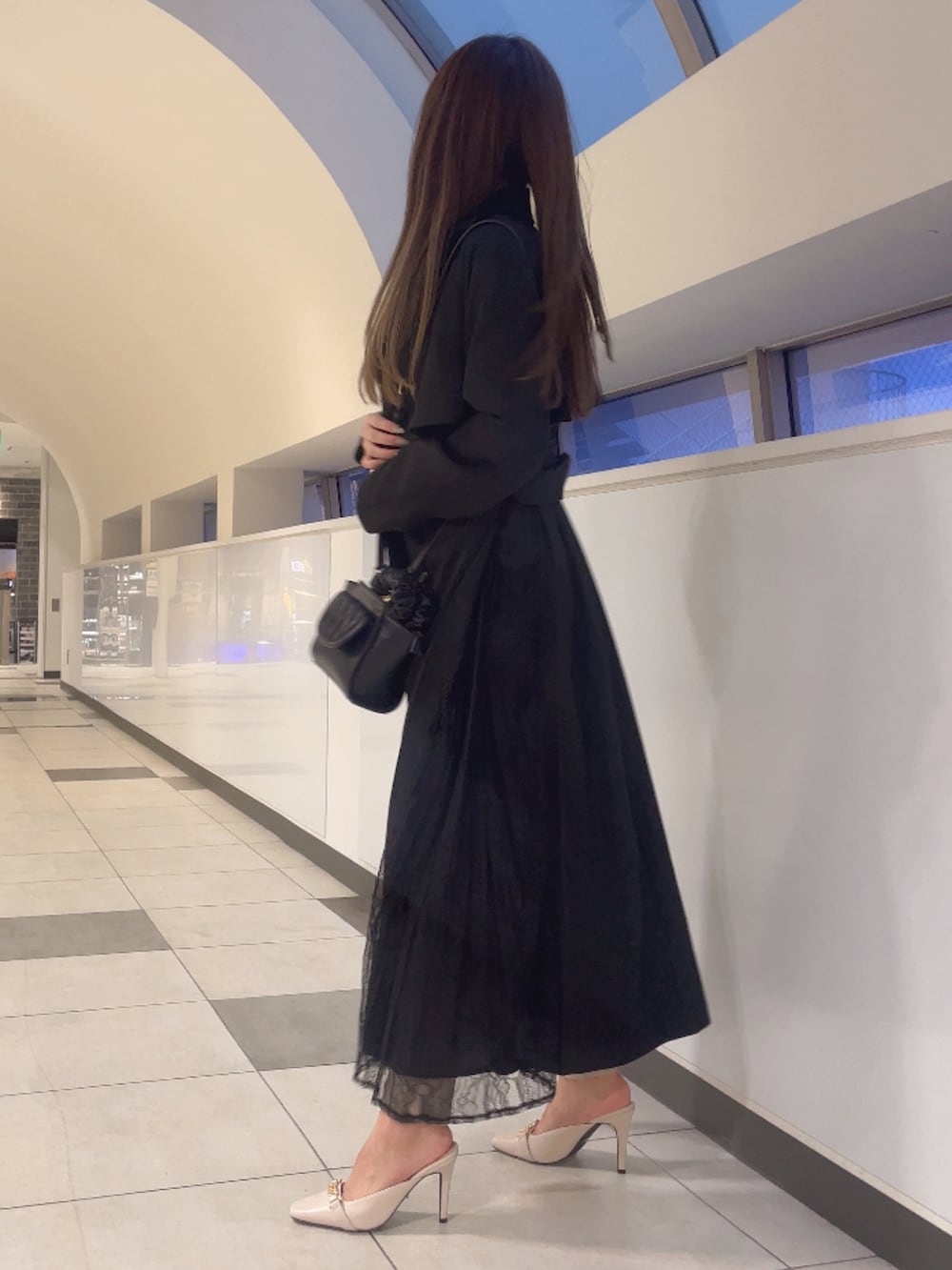 ブラック系のトレンチコート、ブラック系のニット/セーター、ブラック系のハンドバッグを着用したレディースの春コーディネートの2枚目の写真