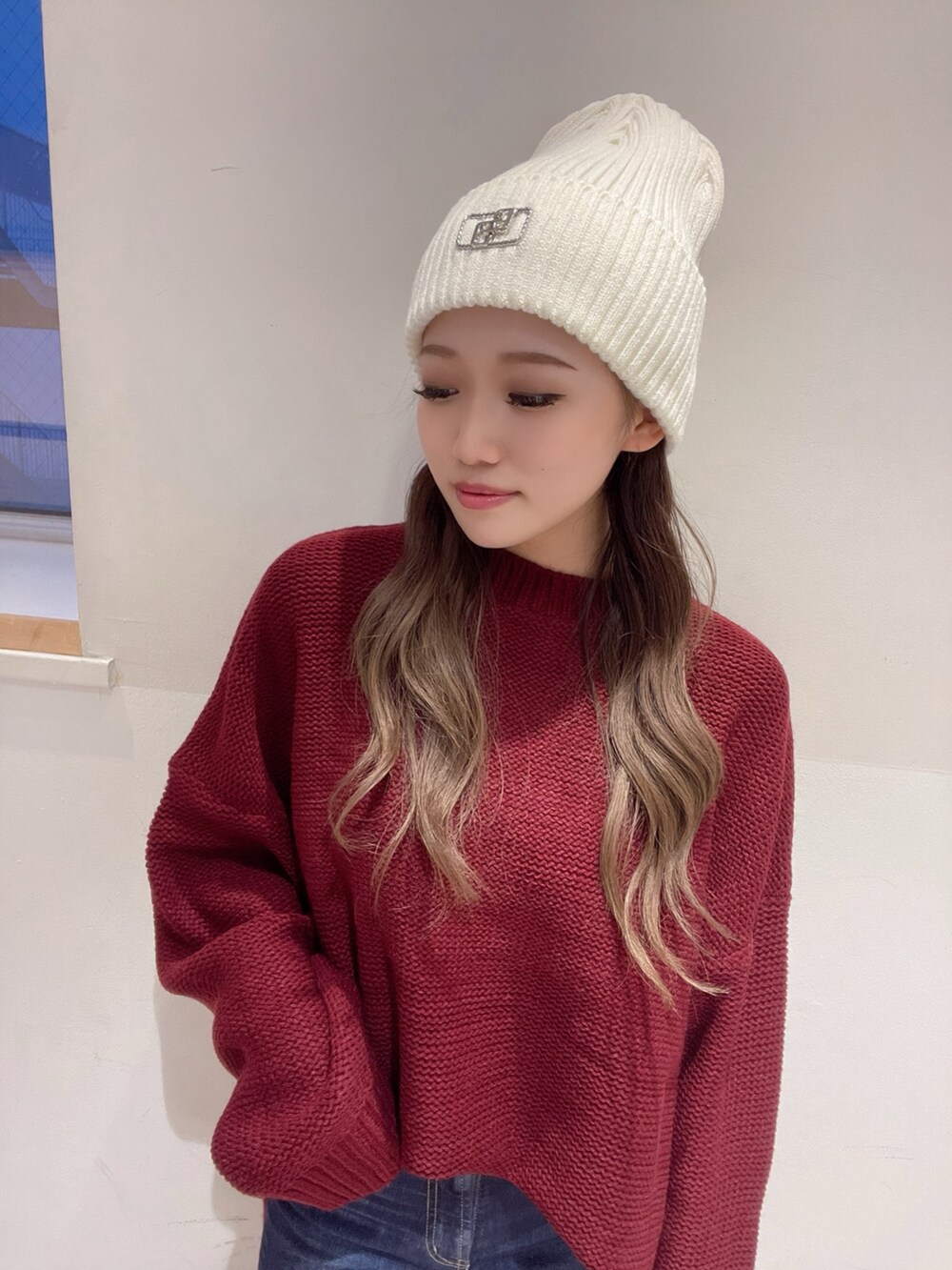 レッド系のニット/セーター、ブルー系のデニムパンツ、ホワイト系のパンプスを着用したレディースの冬コーディネートの4枚目の写真