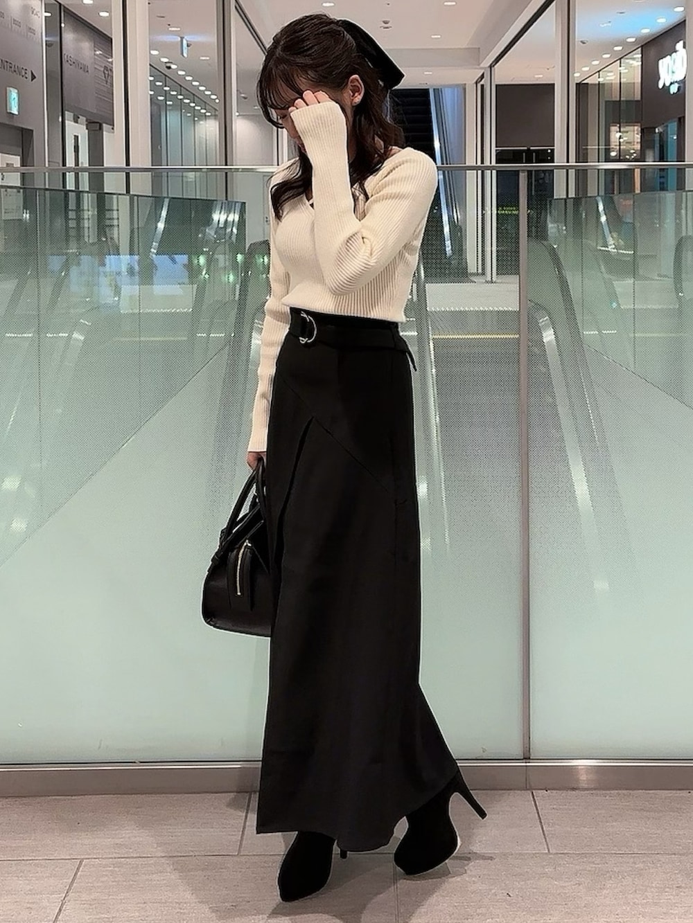 ホワイト系のニット/セーター、ブラック系のスカート、ブラック系のブーツを着用したレディースの冬コーディネートの2枚目の写真