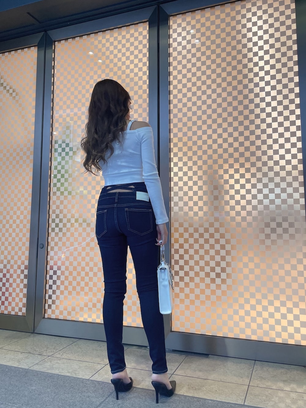 グレー系のライダースジャケット、ホワイト系のTシャツ/カットソー、ブルー系のデニムパンツを着用したレディースの冬コーディネートの3枚目の写真