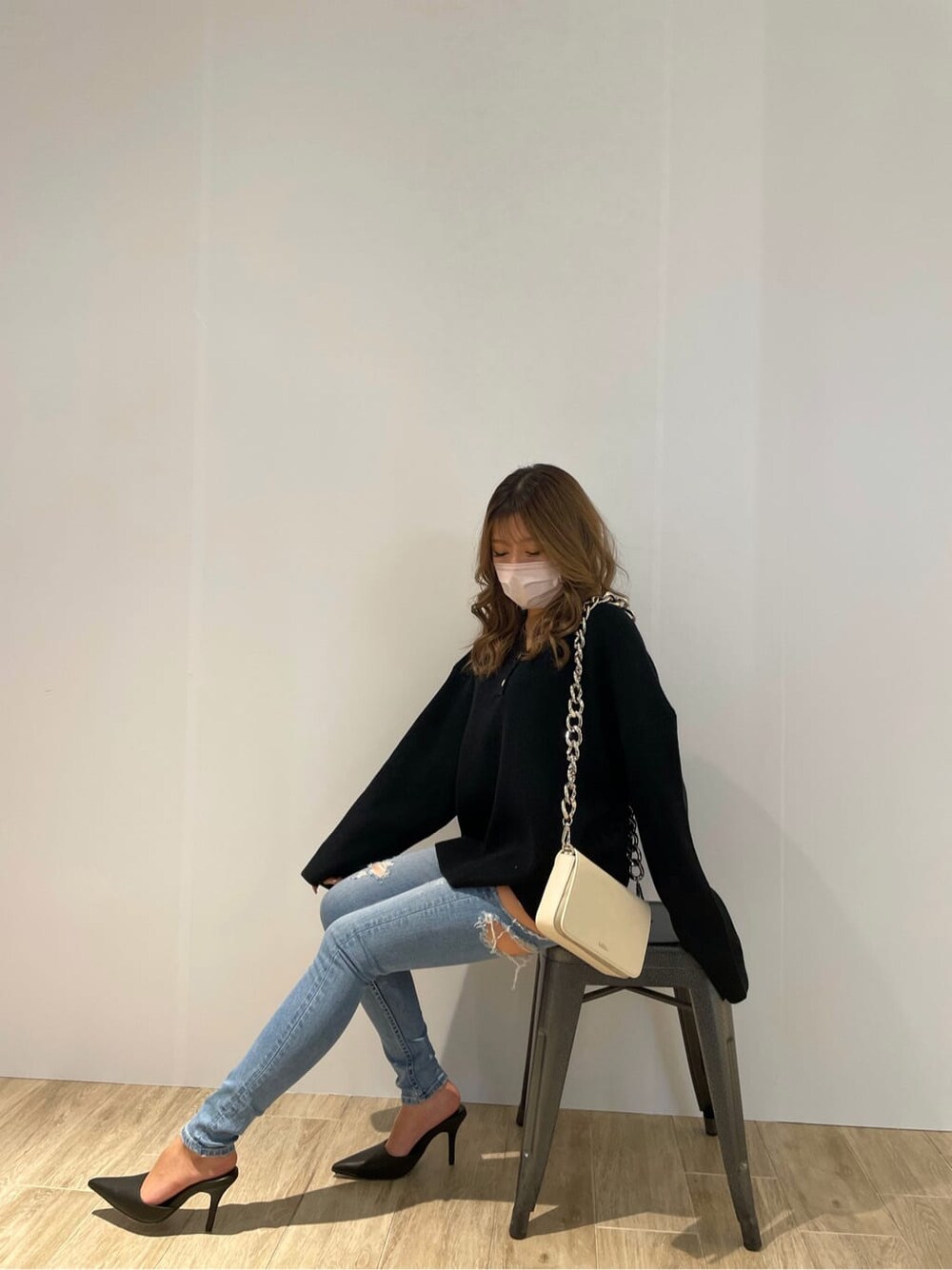 ブラック系のパンプス、ホワイト系のショルダーバッグ、ブルー系のデニムパンツを着用したレディースの冬コーディネートの3枚目の写真