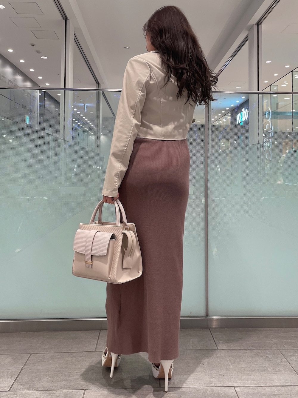 ブラック系のワンピース、ホワイト系のライダースジャケット、ホワイト系のパンプスを着用したレディースの冬コーディネートの3枚目の写真