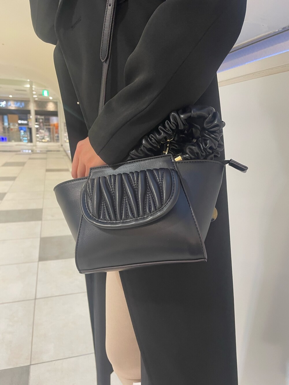 ブラック系のトレンチコート、ブラック系のニット/セーター、ブラック系のハンドバッグを着用したレディースの春コーディネートの6枚目の写真