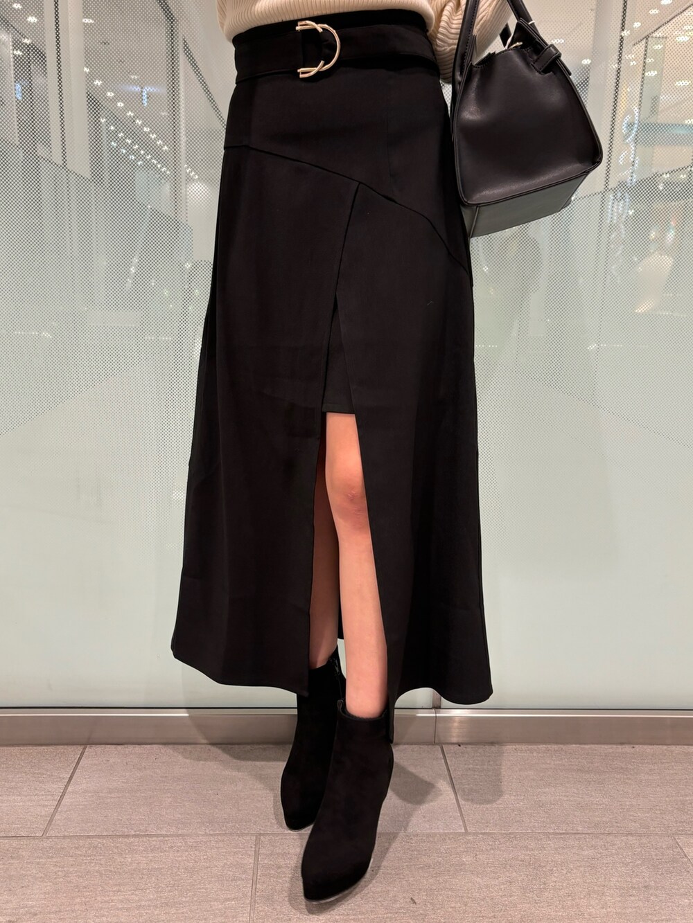 ホワイト系のニット/セーター、ブラック系のスカート、ブラック系のブーツを着用したレディースの冬コーディネートの8枚目の写真