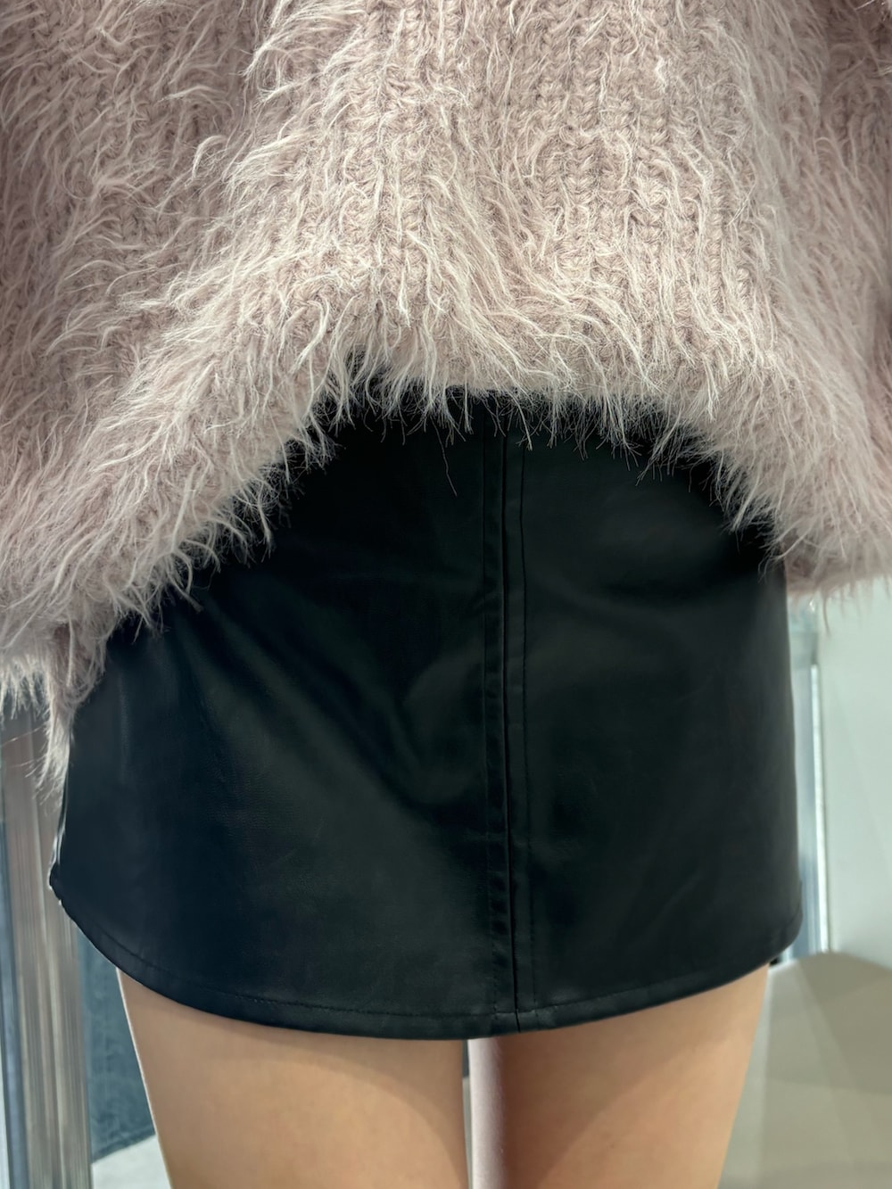 ブラック系のスカート、ピンク系のニット/セーター、ブラック系のブーツを着用したレディースの秋コーディネートの4枚目の写真