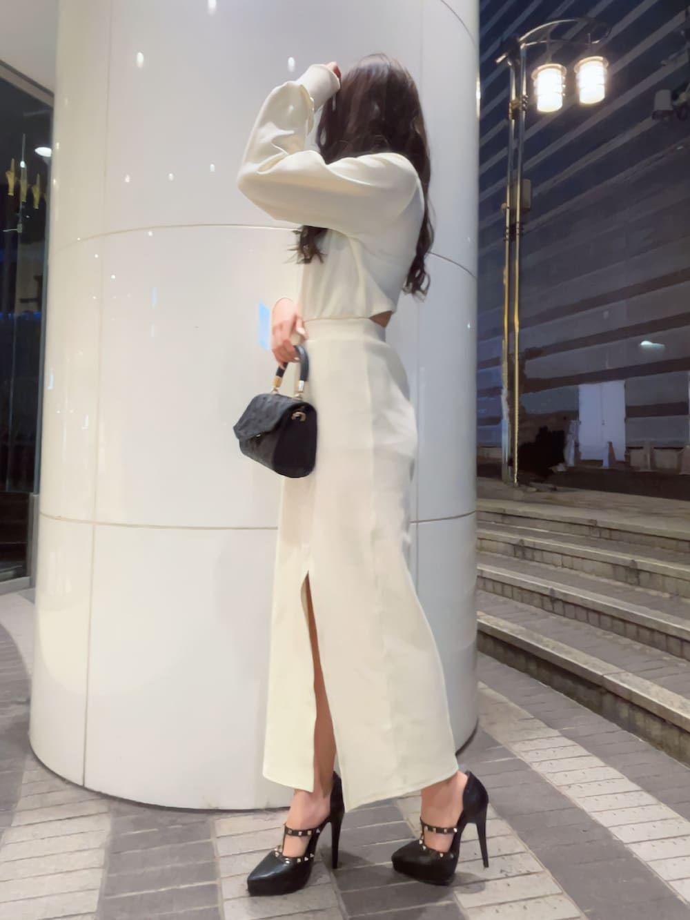 ホワイト系のワンピース、ブラック系のハンドバッグ、ブラック系のパンプスを着用したレディースの冬コーディネートの3枚目の写真