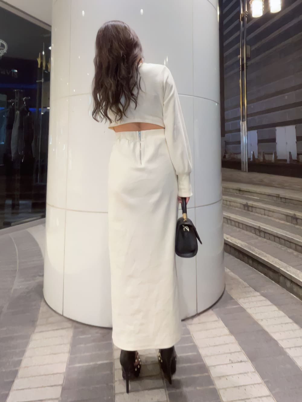 ホワイト系のワンピース、ブラック系のハンドバッグ、ブラック系のパンプスを着用したレディースの冬コーディネートの2枚目の写真