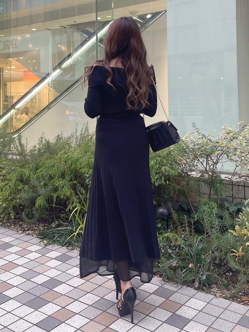 ブラック系のハンドバッグ、ブラック系のパンプス、ブラック系のワンピースを着用したレディースの冬コーディネートの2枚目の写真