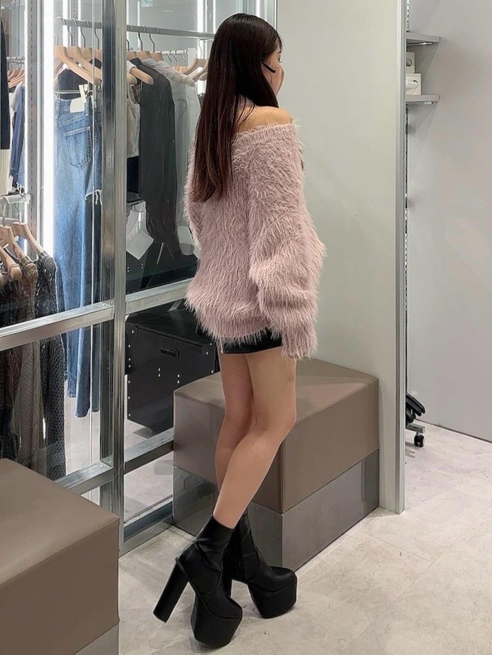 ブラック系のスカート、ピンク系のニット/セーター、ブラック系のブーツを着用したレディースの秋コーディネートの2枚目の写真