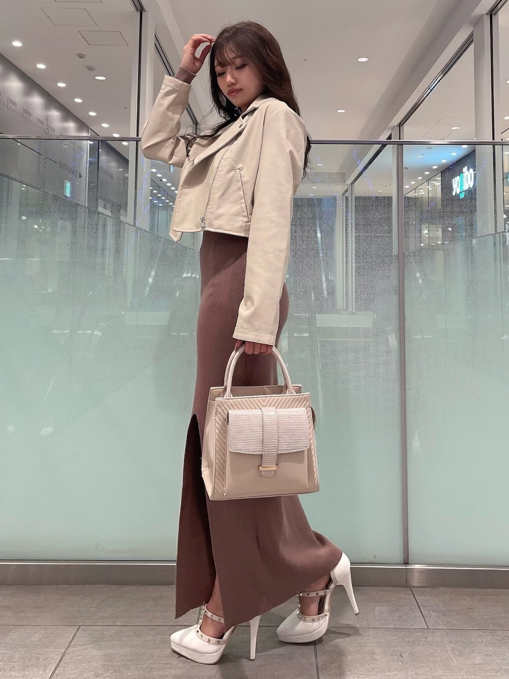 ブラック系のワンピース、ホワイト系のライダースジャケット、ホワイト系のパンプスを着用したレディースの冬コーディネートの2枚目の写真