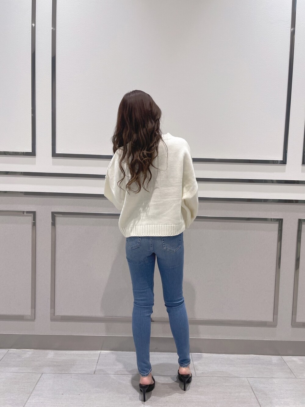 ホワイト系のニット/セーター、ブルー系のデニムパンツ、ブラック系のパンプスを着用したレディースの冬コーディネートの2枚目の写真