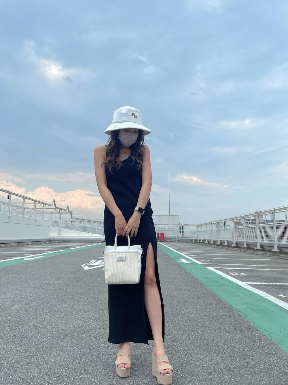 ホワイト系のサンダル、ホワイト系のハンドバッグ、ブラック系のワンピースを着用したレディースの夏コーディネートの2枚目の写真