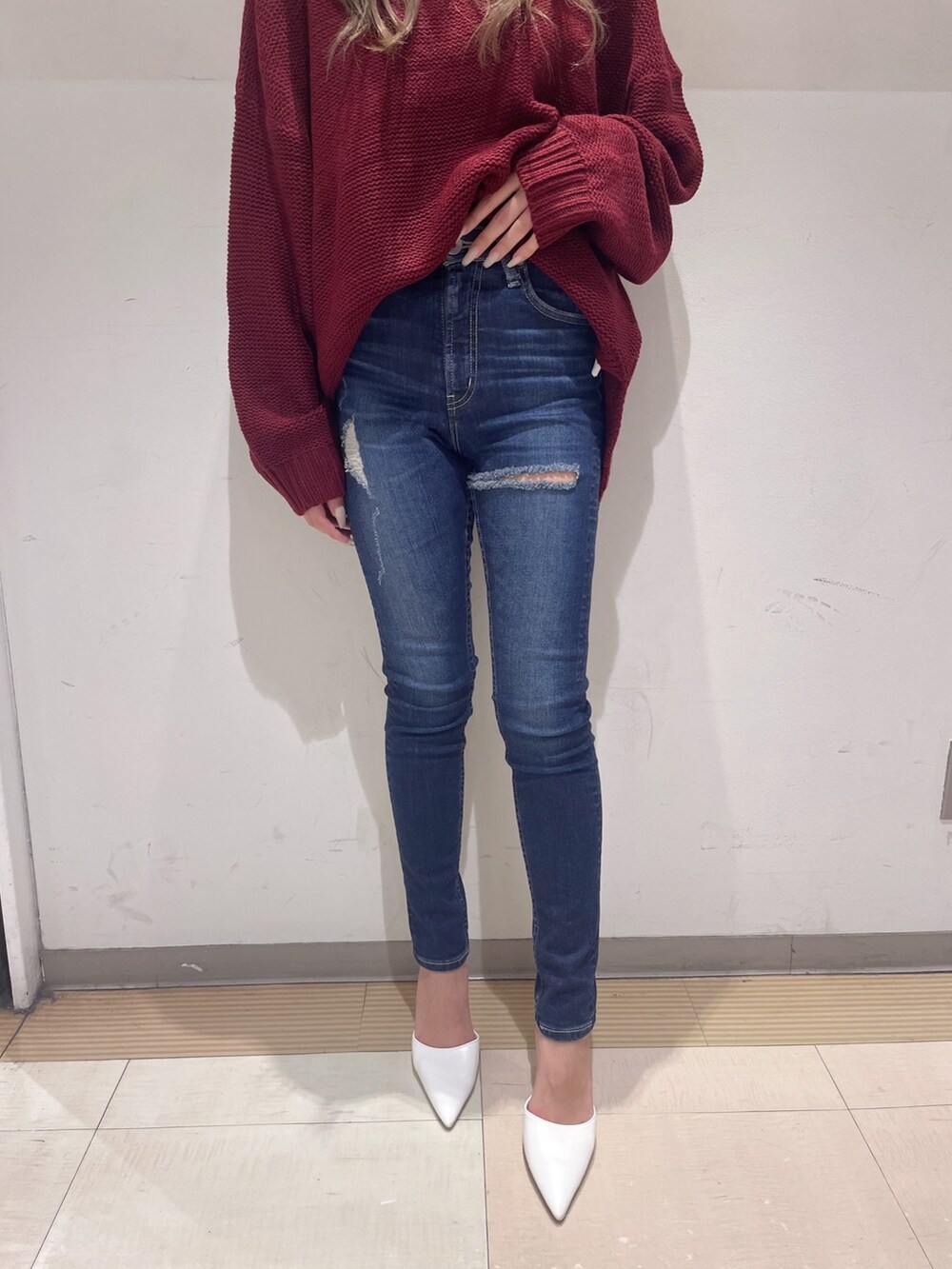 レッド系のニット/セーター、ブルー系のデニムパンツ、ホワイト系のパンプスを着用したレディースの冬コーディネートの3枚目の写真