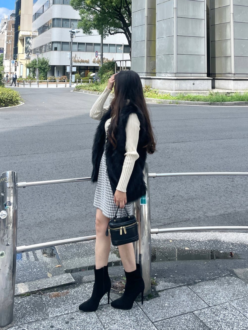 ブラック系のハンドバッグ、ホワイト系のニット/セーター、ブラック系のベストを着用したレディースの秋コーディネートの2枚目の写真