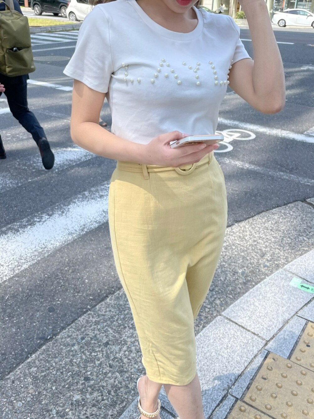 ホワイト系のTシャツ/カットソー、イエロー系のスカート、ホワイト系のサンダルを着用したレディースの春コーディネートの3枚目の写真