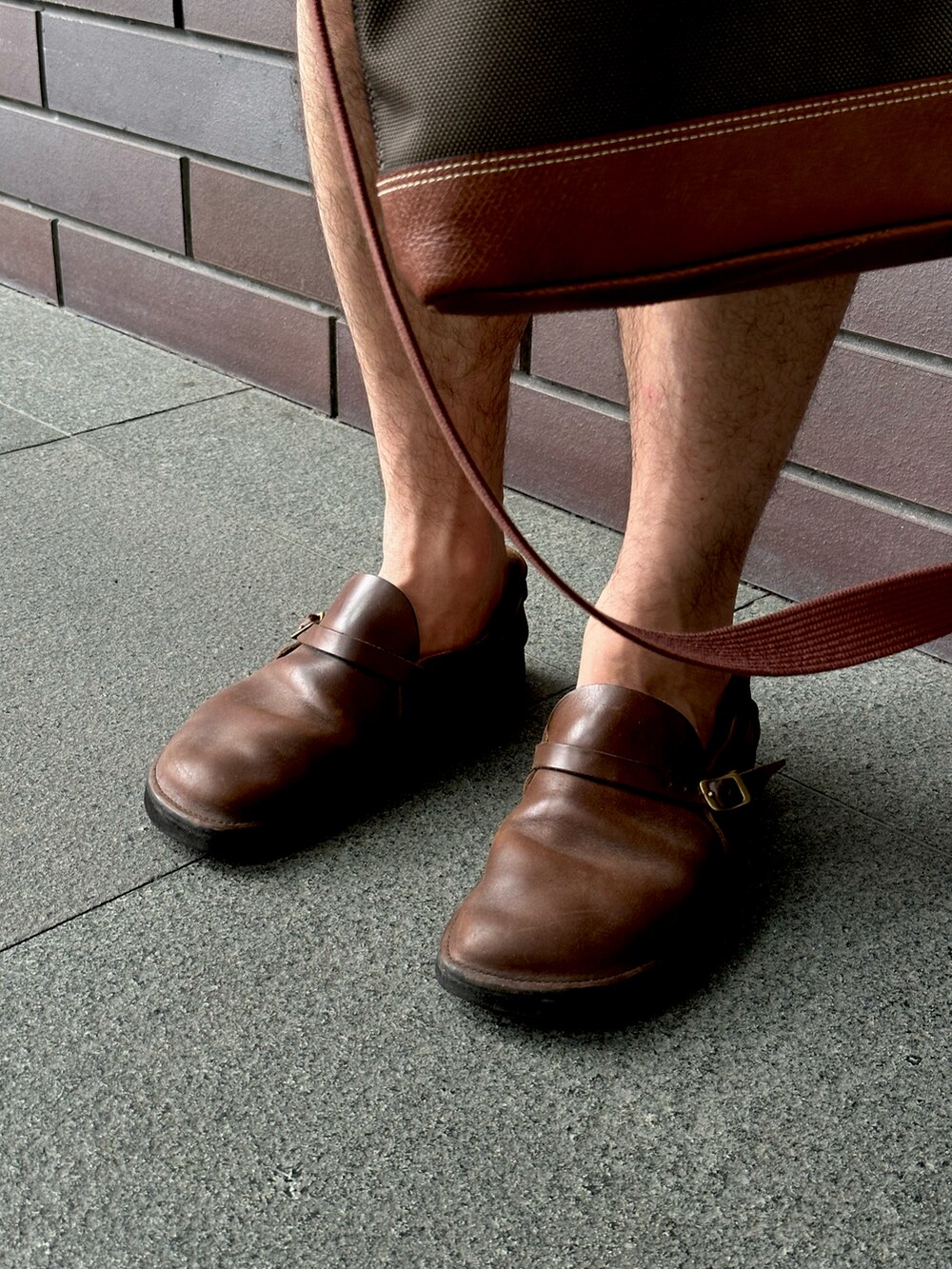 ブラウン系のローファー、ブラック系のその他パンツ、ブラウン系のビジネスバッグを着用したメンズの冬コーディネートの3枚目の写真