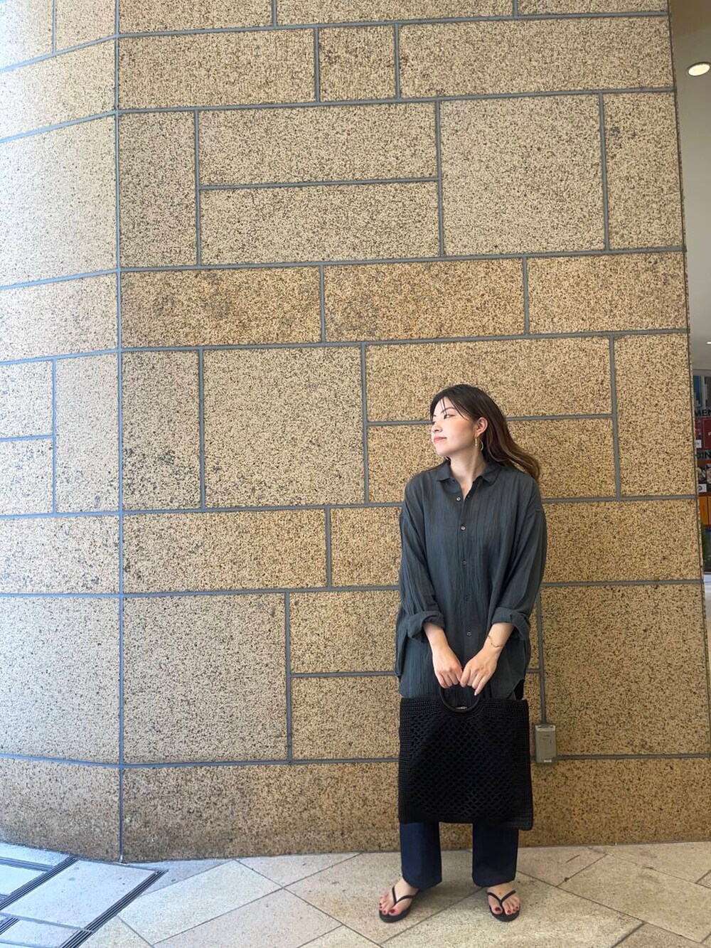 ブラック系のサンダル、ブルー系のデニムパンツ、ブラック系のトートバッグを着用したレディースの夏コーディネートの2枚目の写真