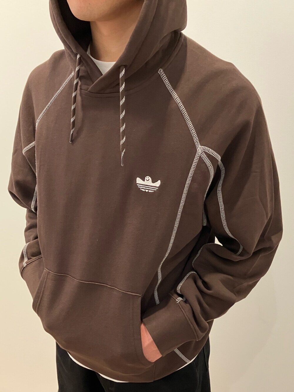 ブラウン系のパーカー、ホワイト系のトップス、ブラウン系のスニーカーを着用したメンズの冬コーディネートの3枚目の写真