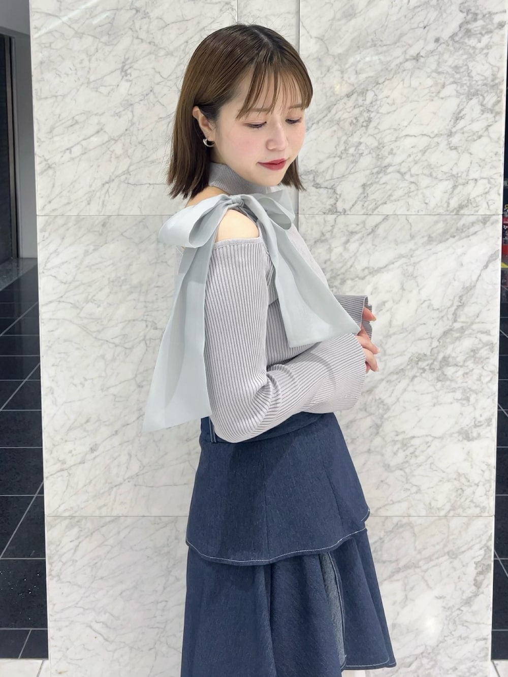 グレー系のニット/セーター、ブルー系のスカート、ブラック系のパンプスを着用したレディースの秋コーディネートの4枚目の写真