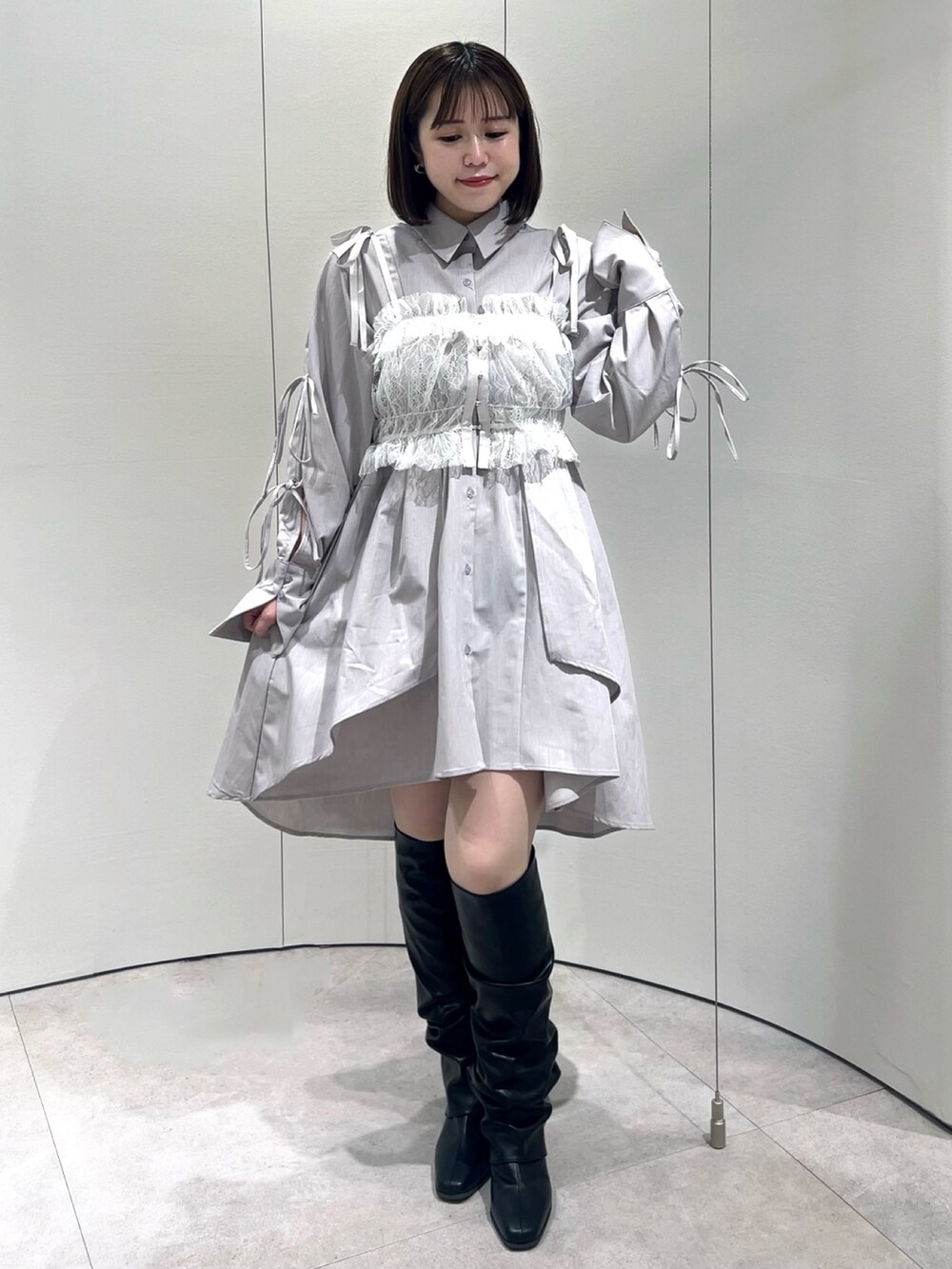 ホワイト系のキャミソール、グレー系のシャツワンピース、ブラック系のブーツを着用したレディースの秋コーディネートの2枚目の写真