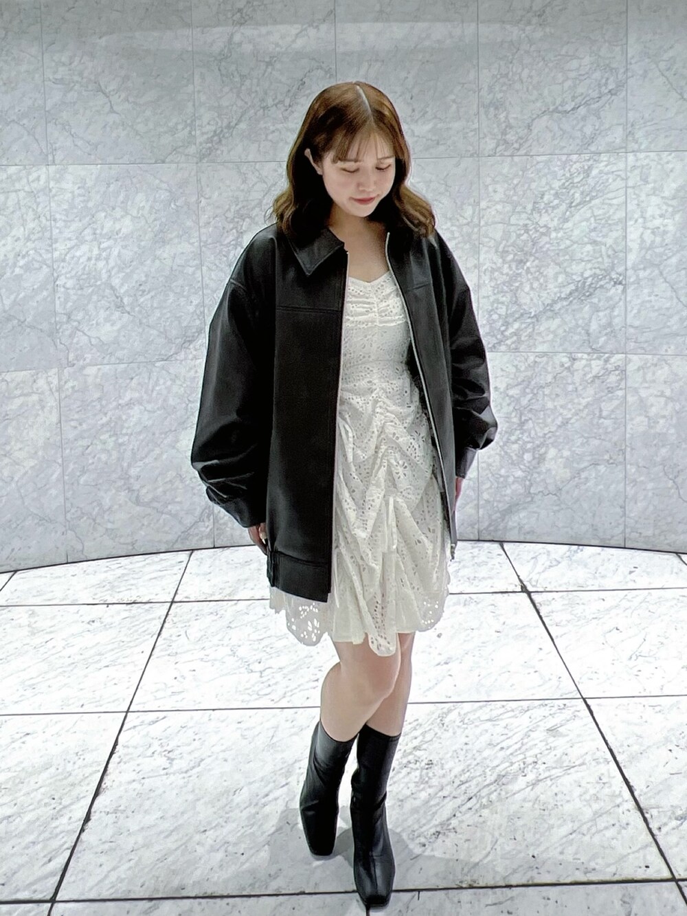 ブラック系のブルゾン、ホワイト系のワンピースを着用したレディースの冬コーディネートの2枚目の写真