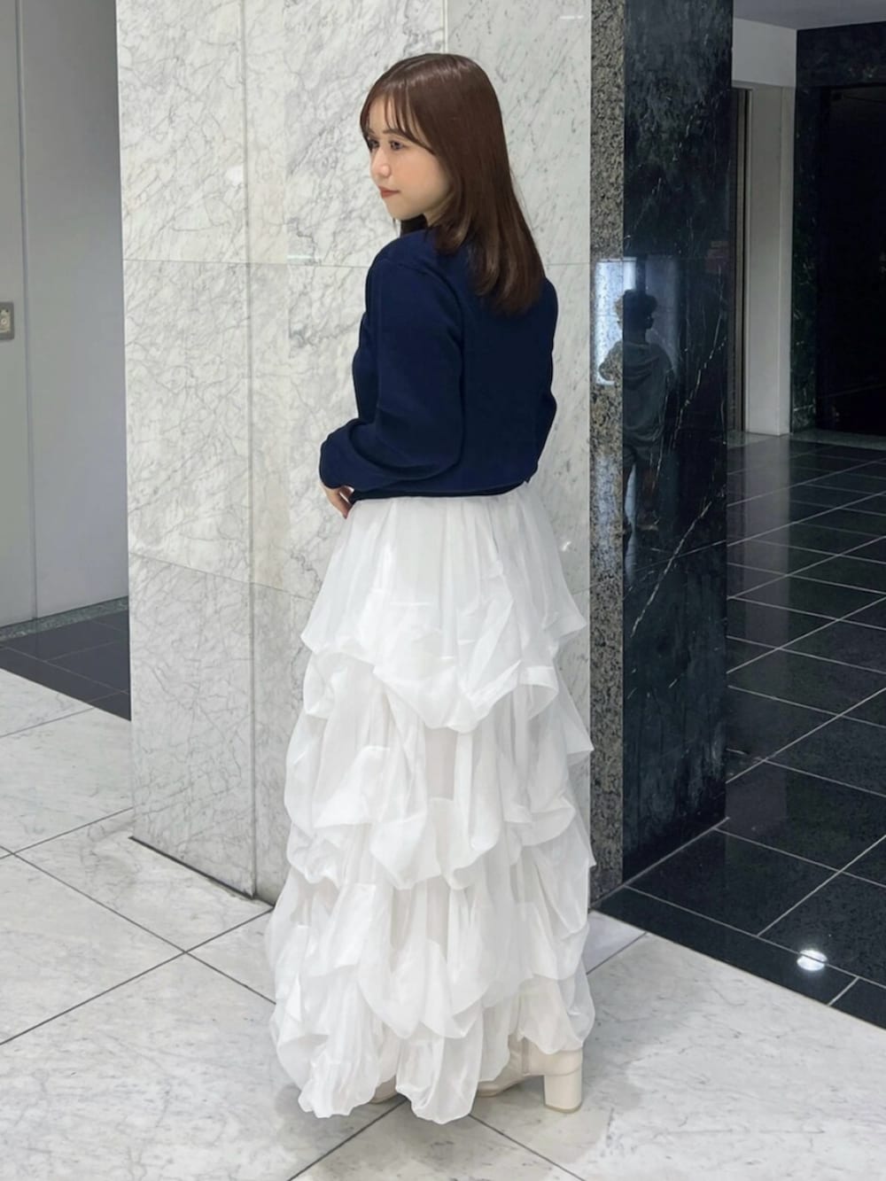 ブルー系のカーディガン/ボレロ、ホワイト系のスカート、ホワイト系のブーツを着用したレディースの秋コーディネートの4枚目の写真