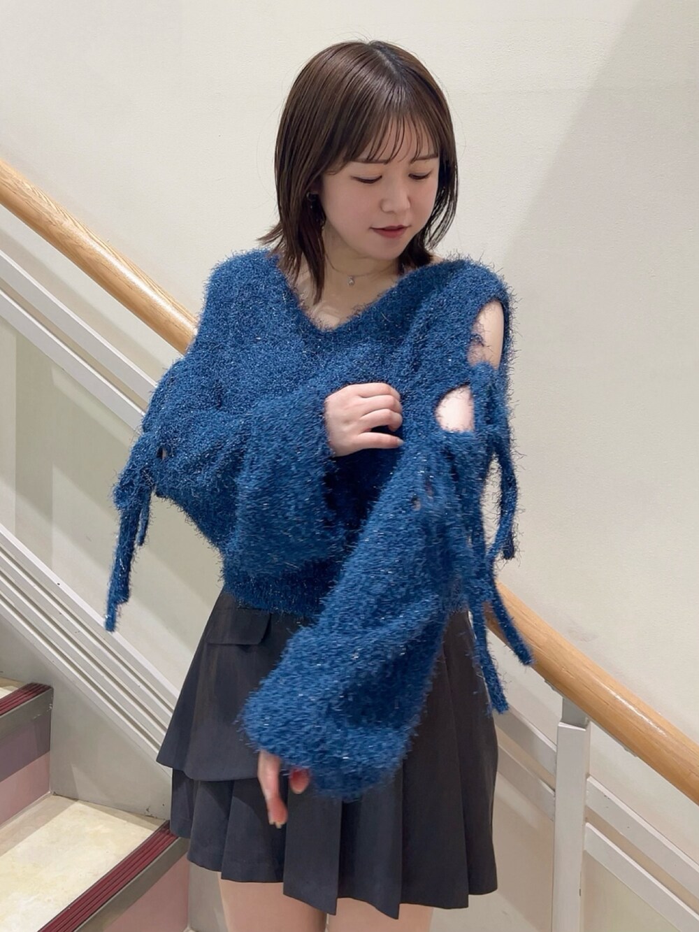 グレー系のスカート、ホワイト系のその他シューズ、ブルー系のニット/セーターを着用したレディースの夏コーディネートの5枚目の写真