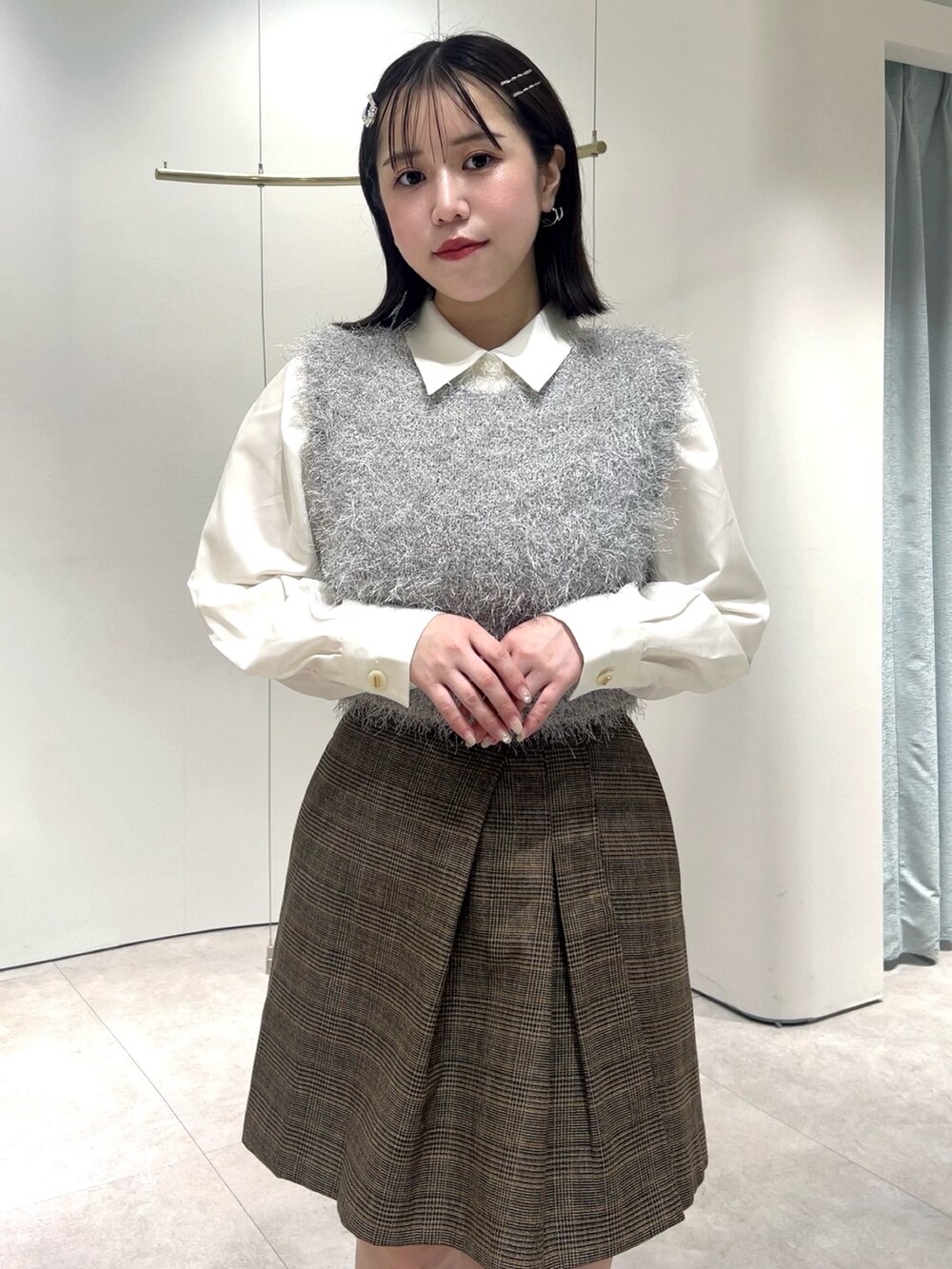 グレー系のニット/セーター、ホワイト系のシャツ/ブラウス、ブラウン系のスカートを着用したレディースの秋コーディネートの6枚目の写真