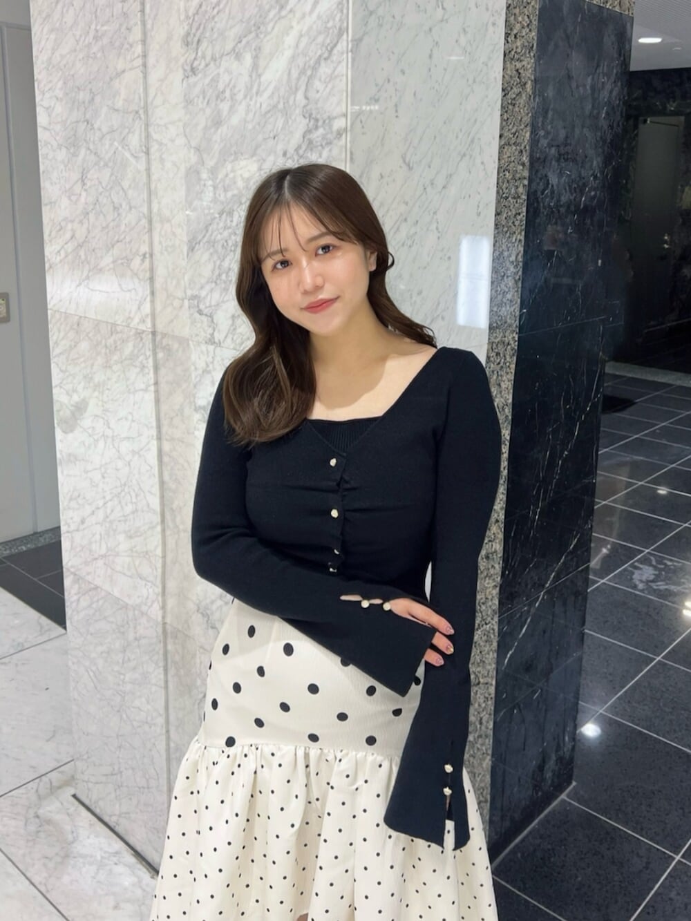 ブラック系のブーツ、ブラック系のニット/セーター、ホワイト系のスカートを着用したレディースの春コーディネートの5枚目の写真