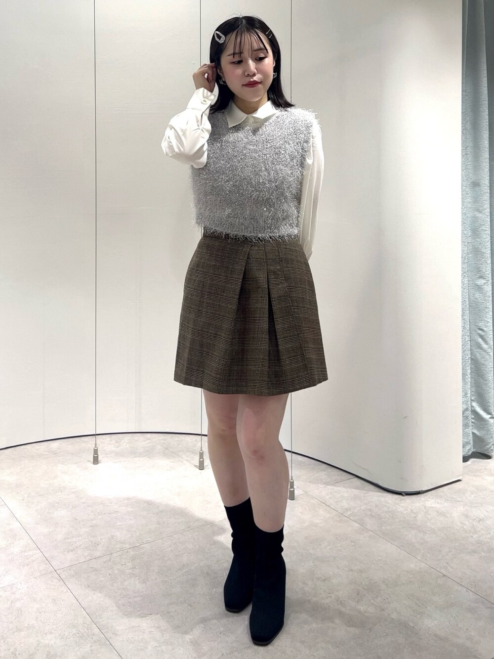 グレー系のニット/セーター、ホワイト系のシャツ/ブラウス、ブラウン系のスカートを着用したレディースの秋コーディネートの4枚目の写真