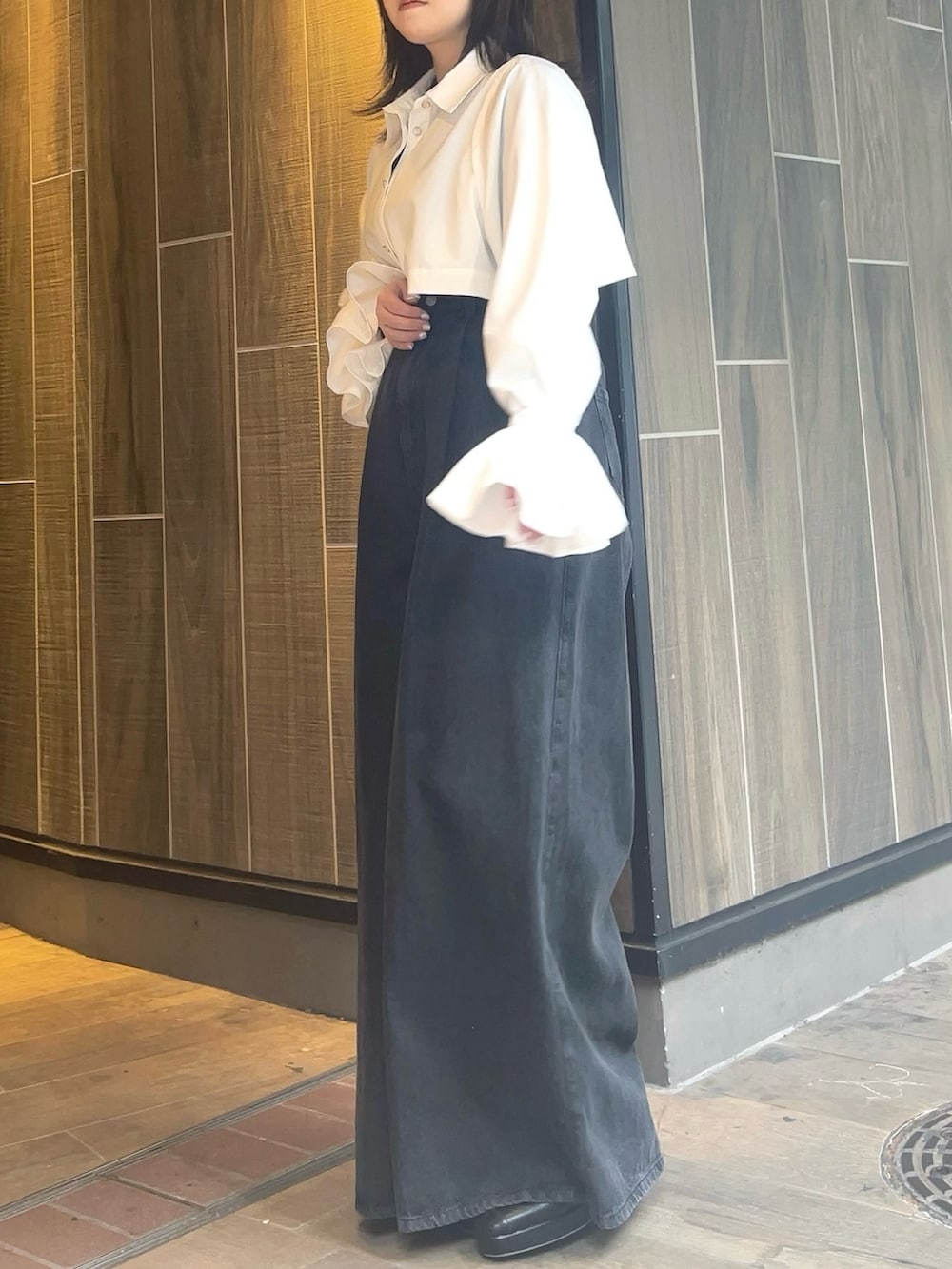 ホワイト系のワンピース、ブラック系のデニムパンツ、ブラック系のブーツを着用したレディースの春コーディネートの6枚目の写真