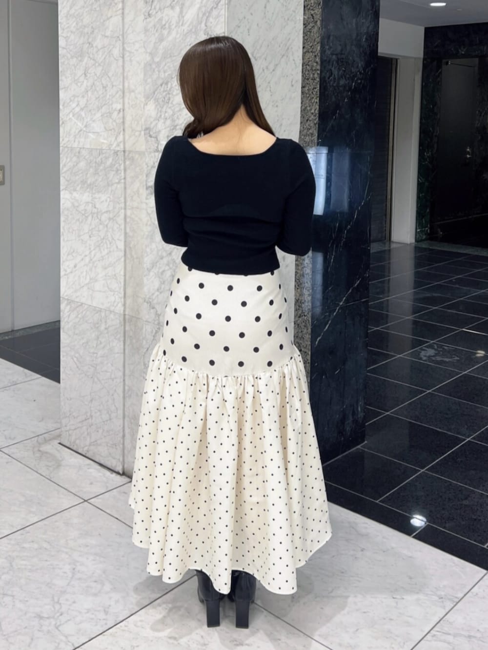 ブラック系のブーツ、ブラック系のニット/セーター、ホワイト系のスカートを着用したレディースの春コーディネートの4枚目の写真