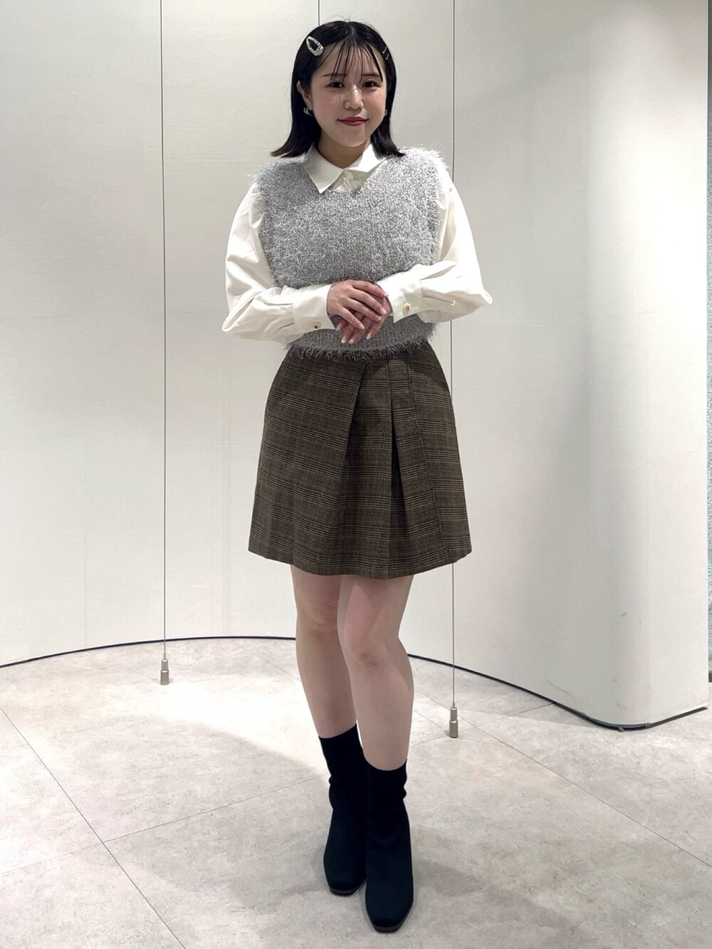 グレー系のニット/セーター、ホワイト系のシャツ/ブラウス、ブラウン系のスカートを着用したレディースの秋コーディネートの3枚目の写真