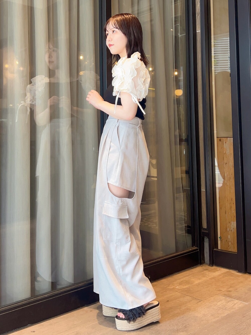 ブラック系のTシャツ/カットソー、グレー系のチノパンツ、ブラック系のサンダルを着用したレディースの夏コーディネートの2枚目の写真